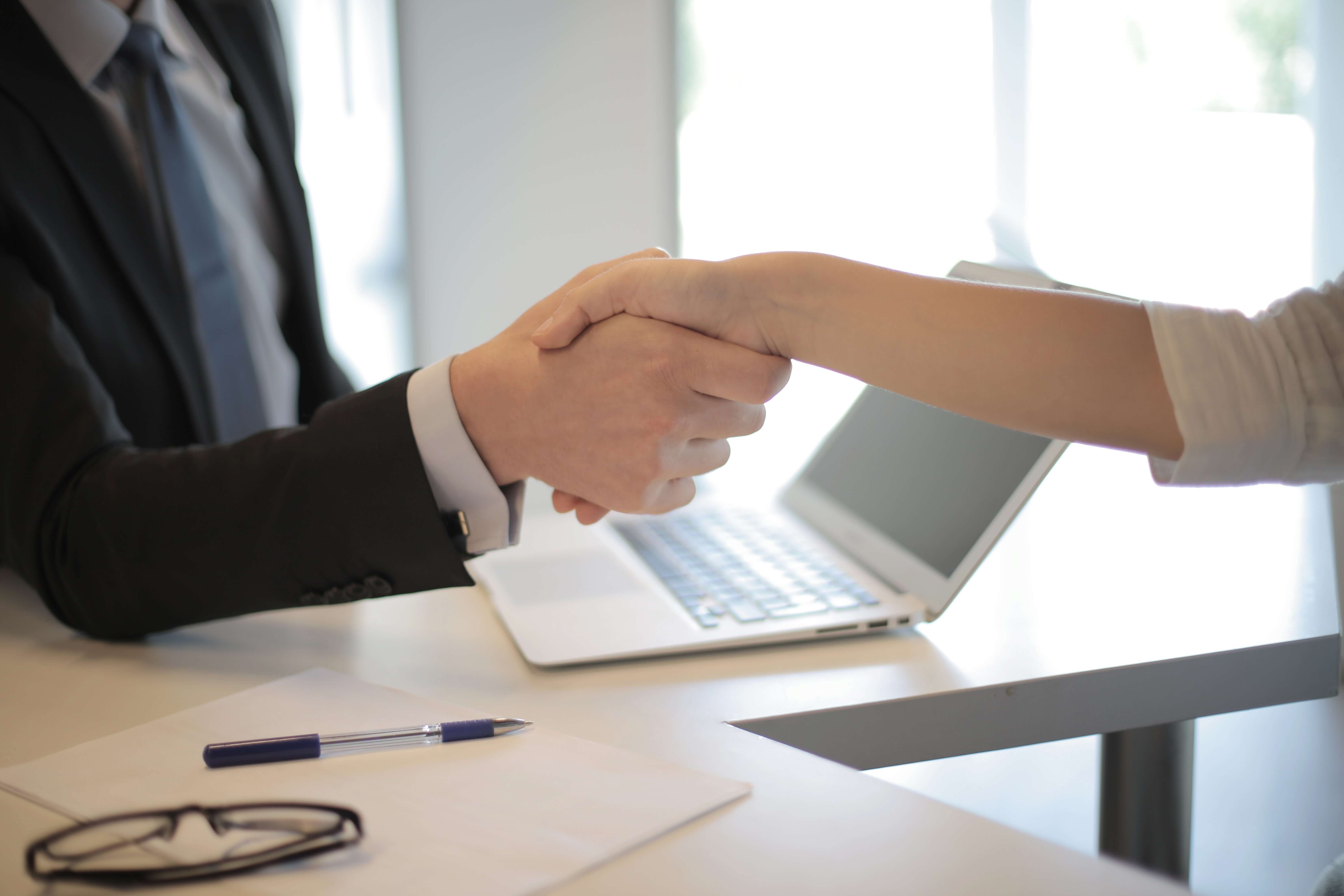 A man's arm, and woman's arm shown shaking hands