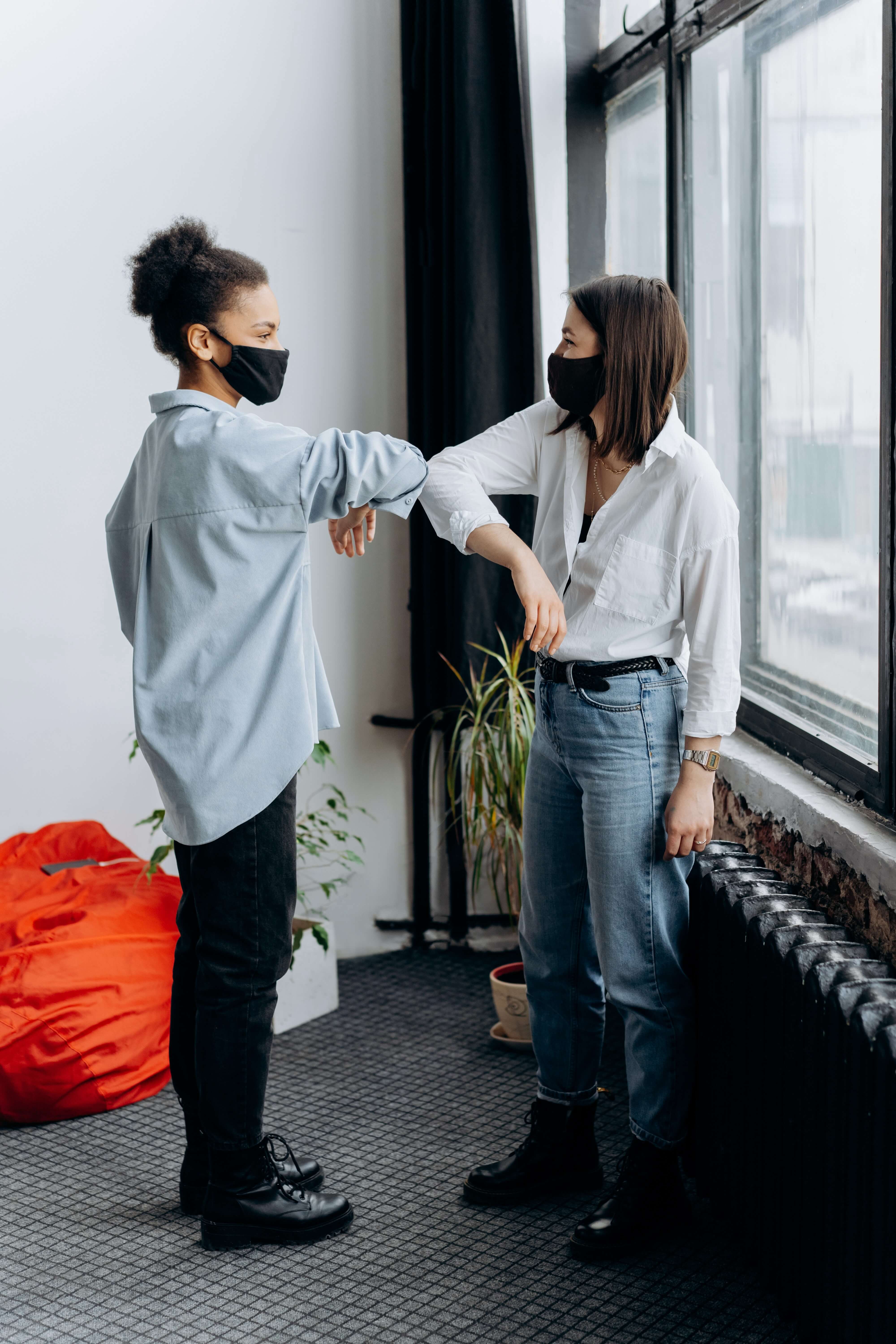 Masked coworkers elbow bump