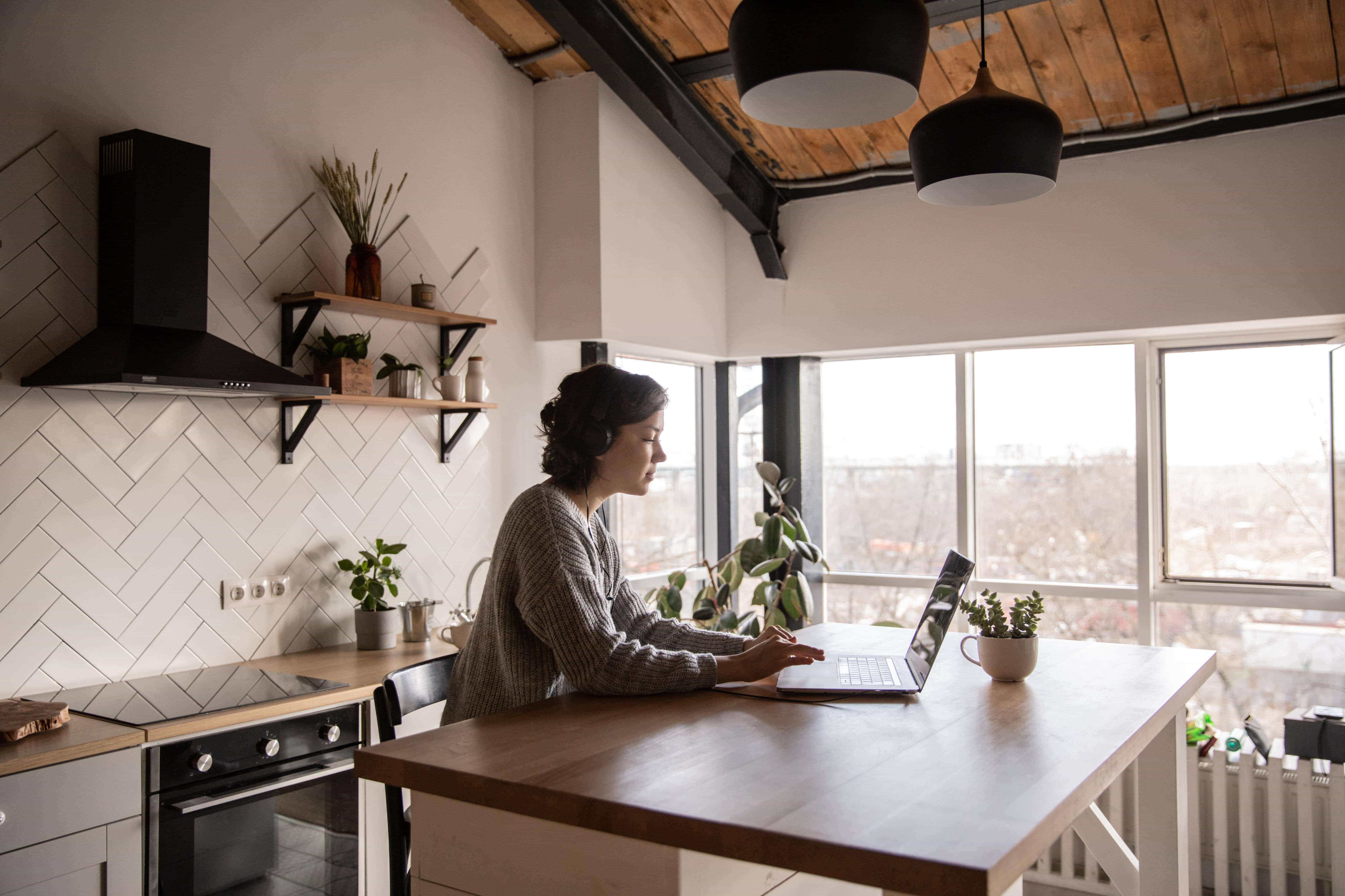 A young women in a kitchen sitting in front of a laptop