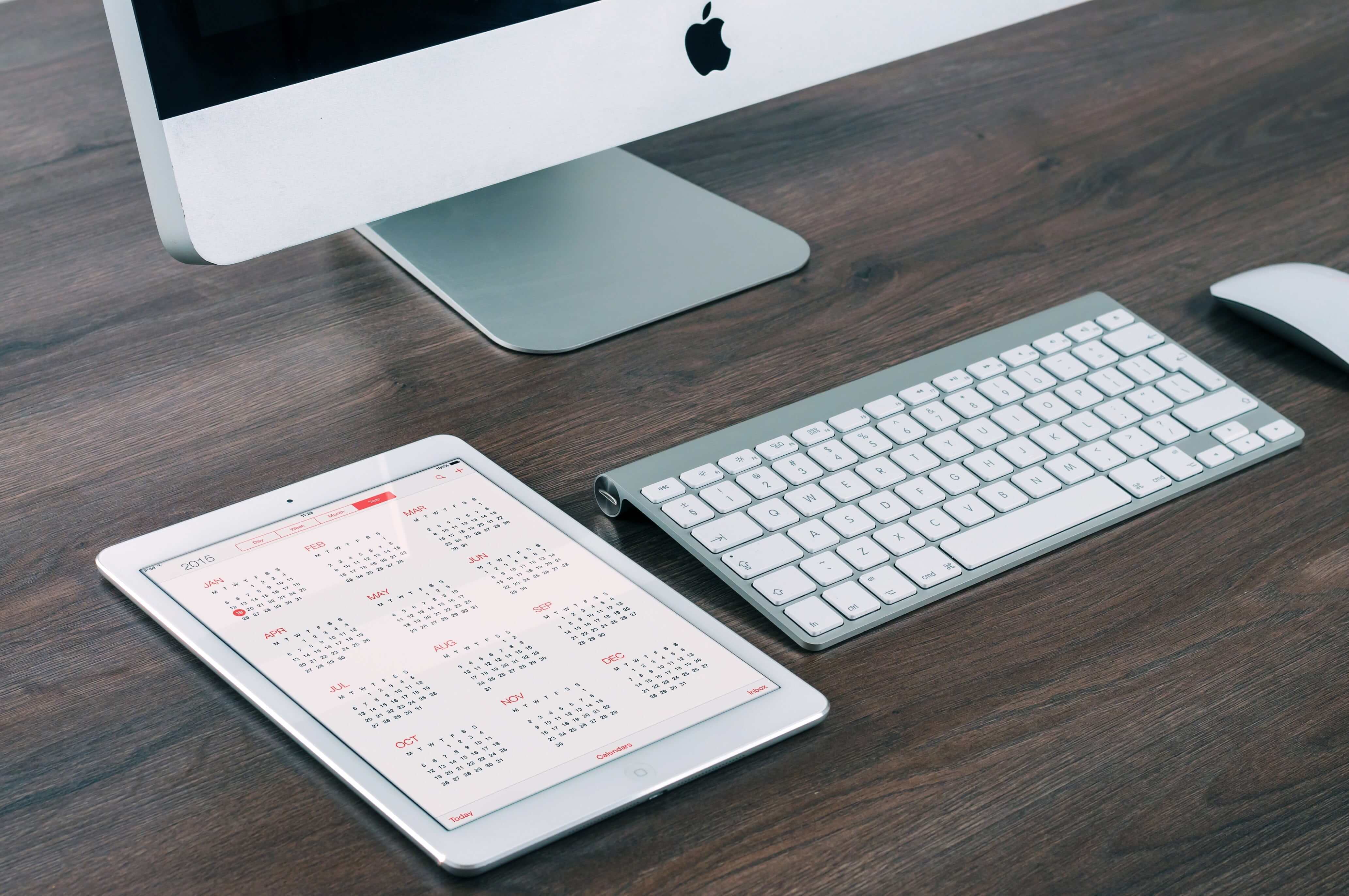 Ipad with calendar view next to a computer