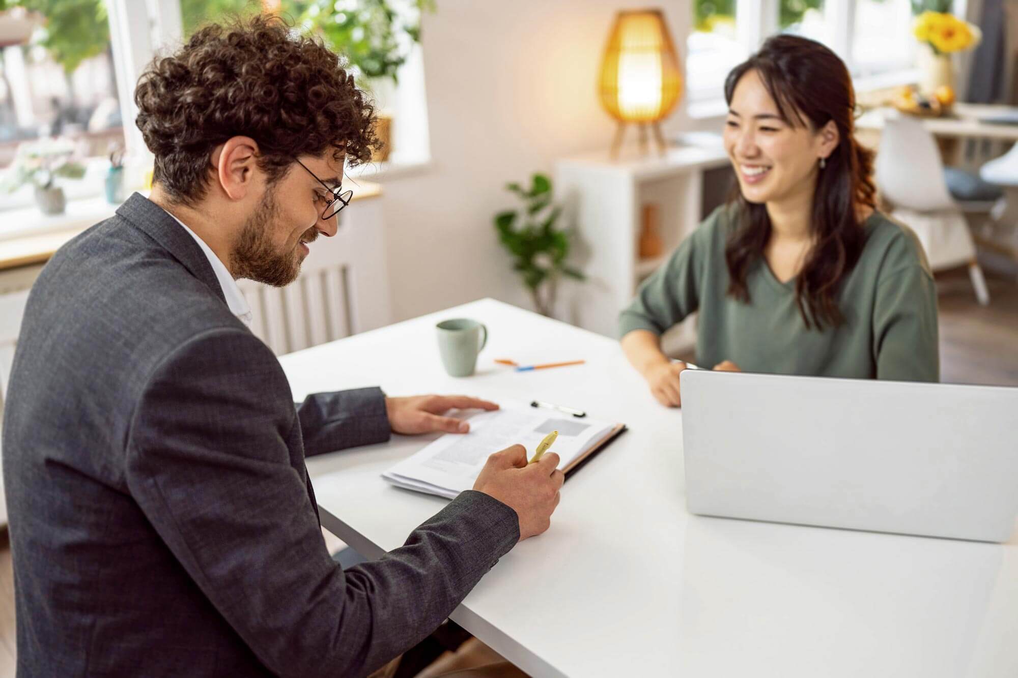 Young Caucasian male candidate signing the contract, during a meeting with a female recruiter Japanese ethnicity.