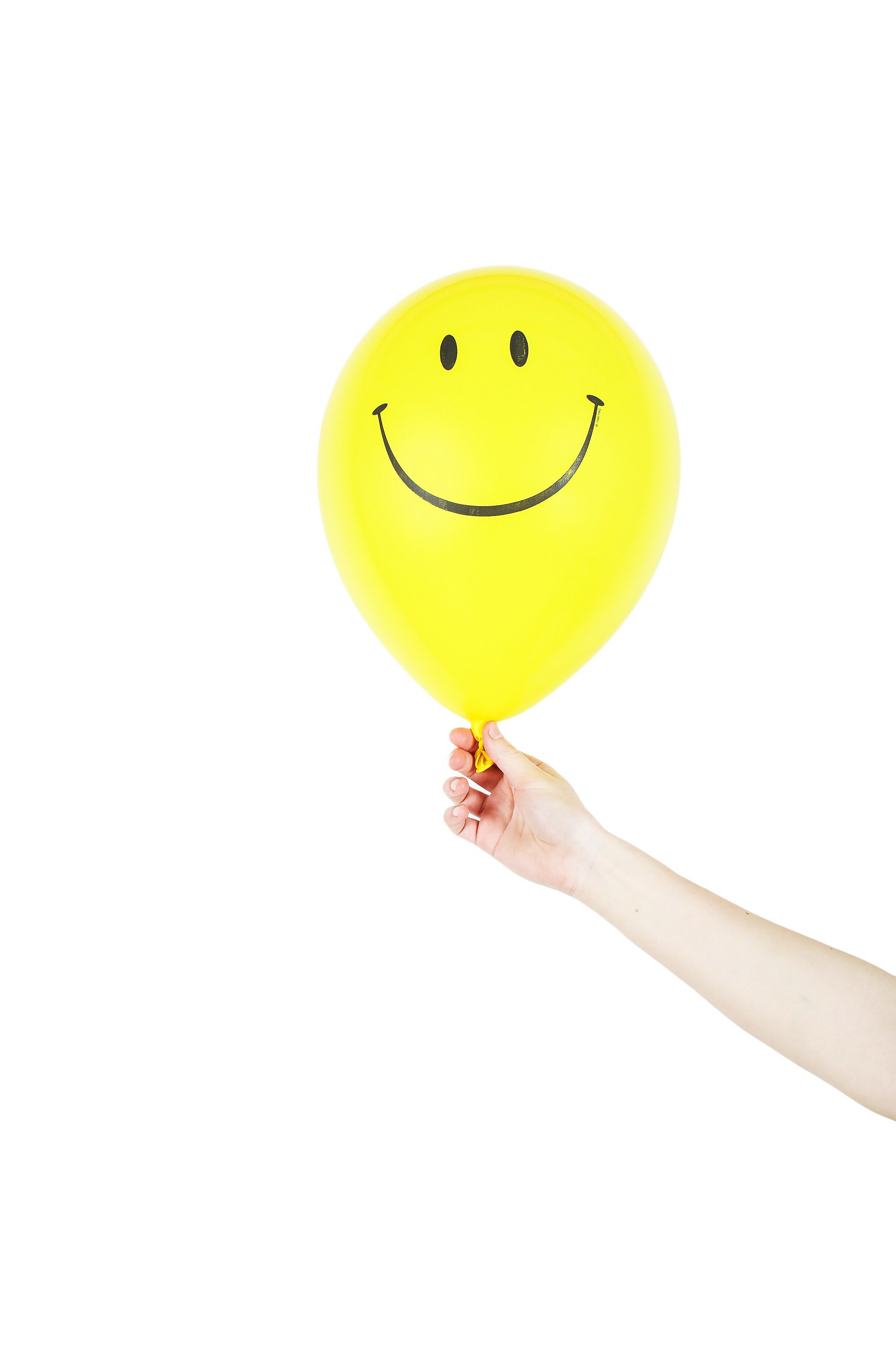 Someone holding a yellow balloon with a smiley face on it