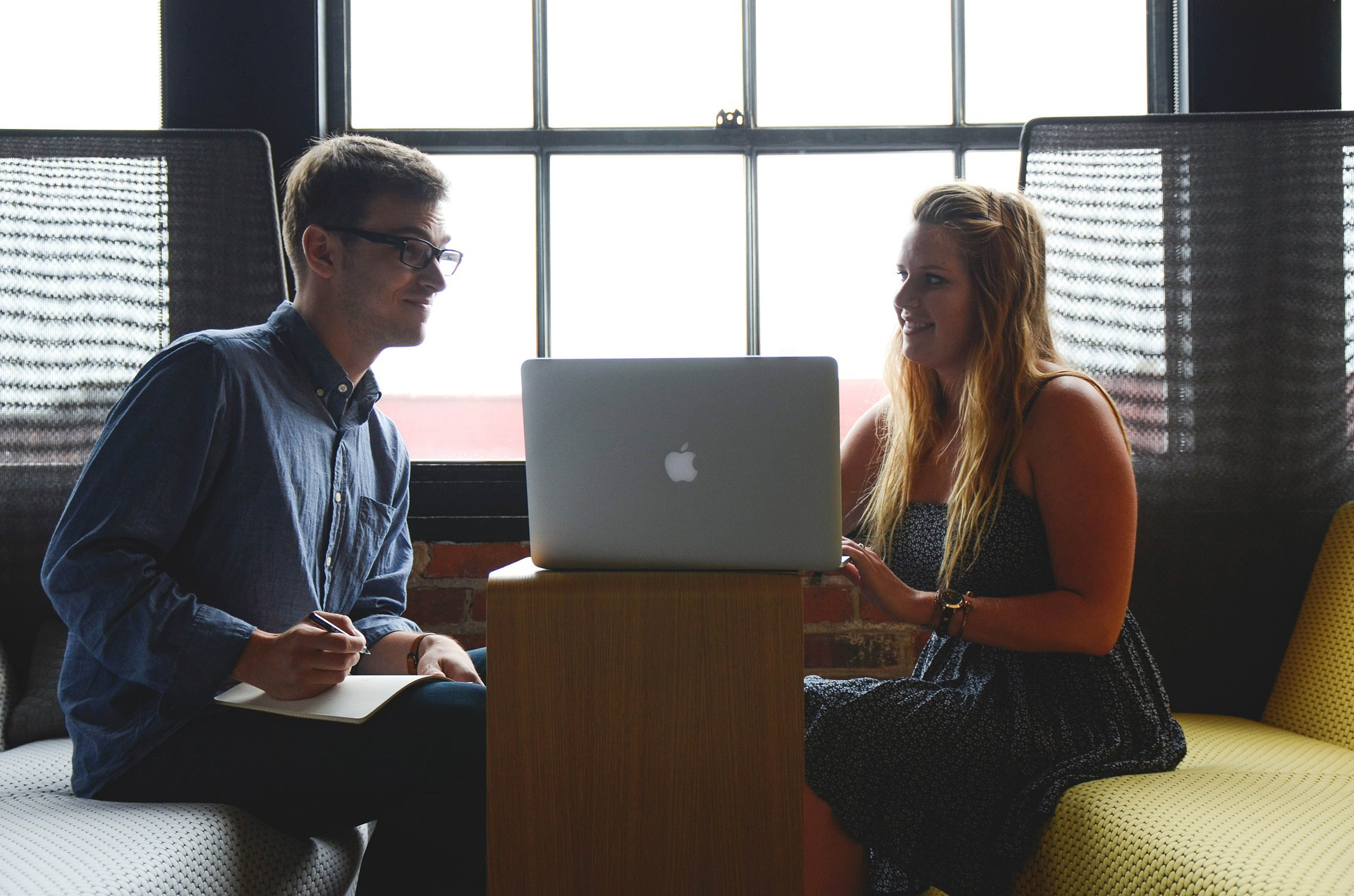 Young woman showing a man something on her laptop screen