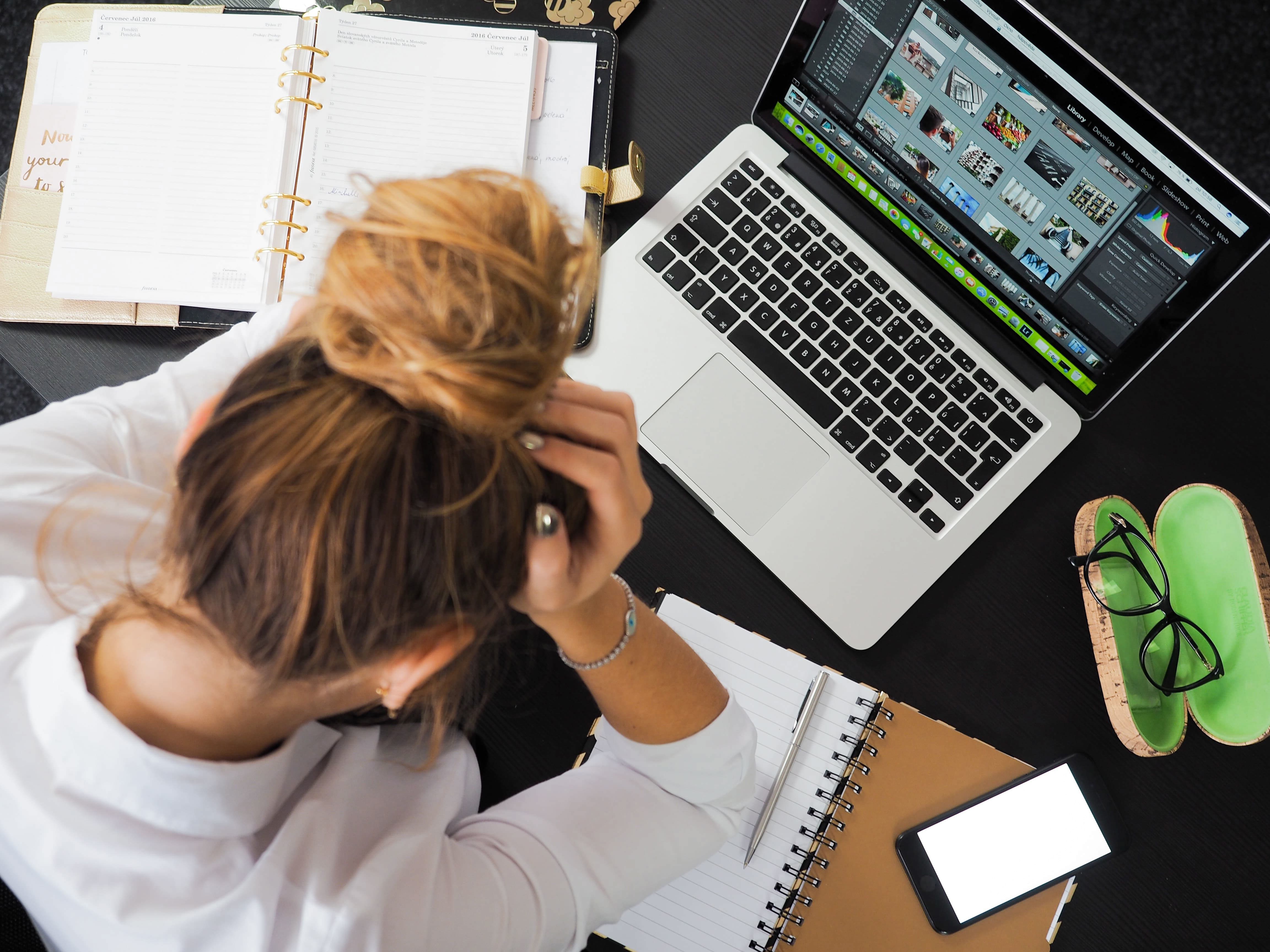 A woman holding her head in front of a laptop