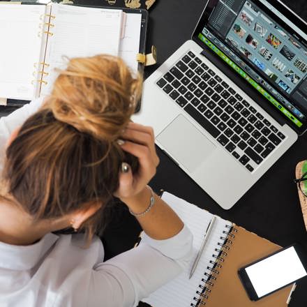 A woman holding her head in front of a laptop