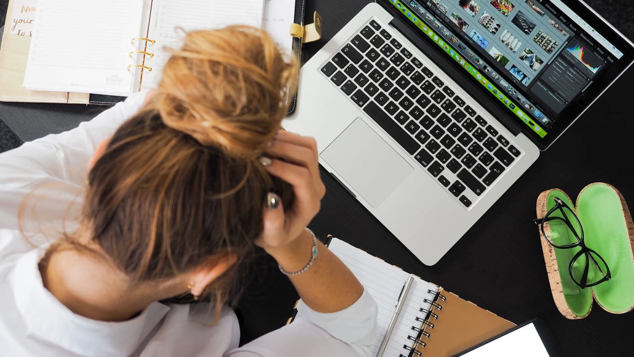 A woman holding her head in front of a laptop