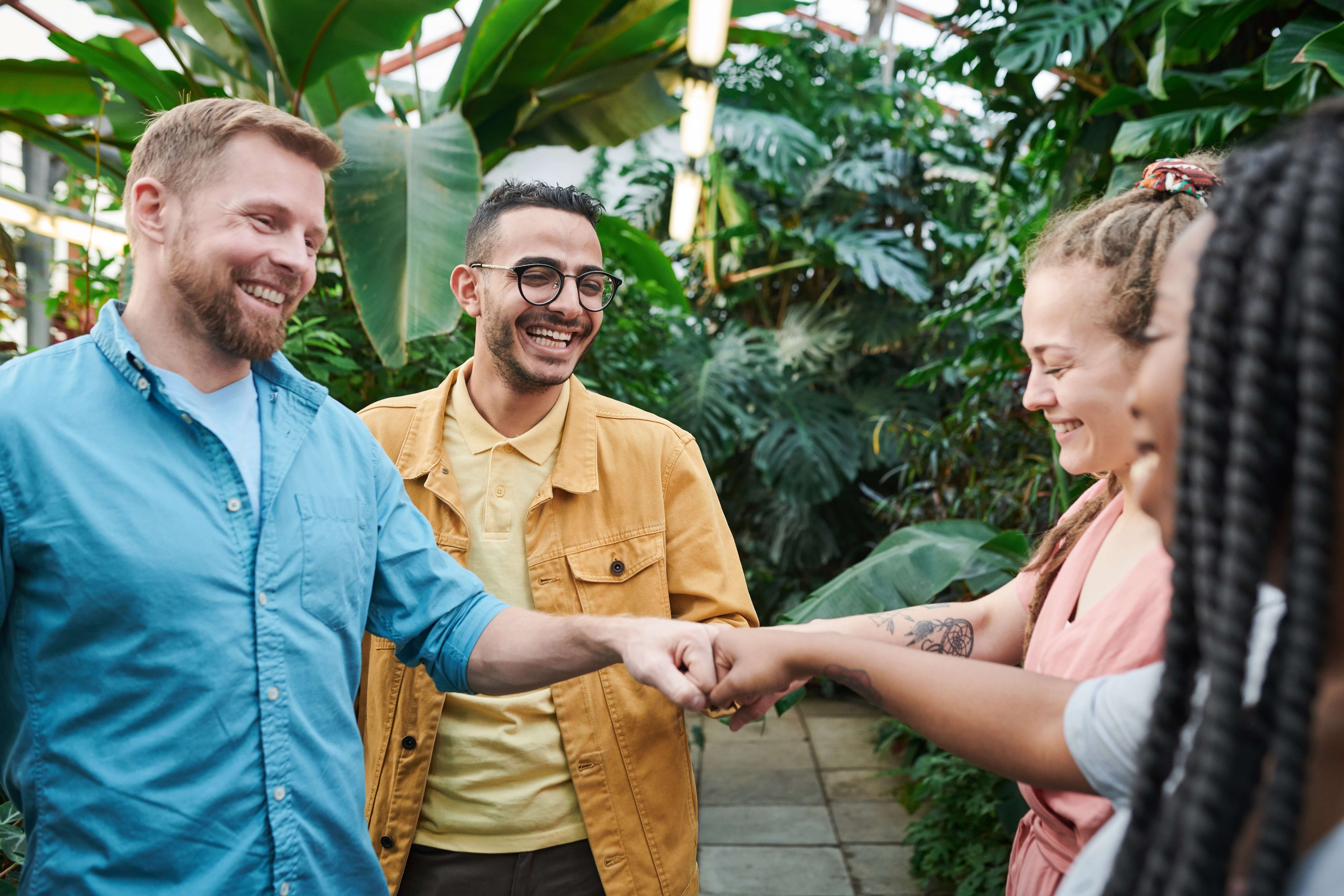 Four people fist bumping against tropical background