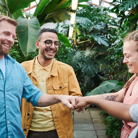 Four people fist bumping against tropical background