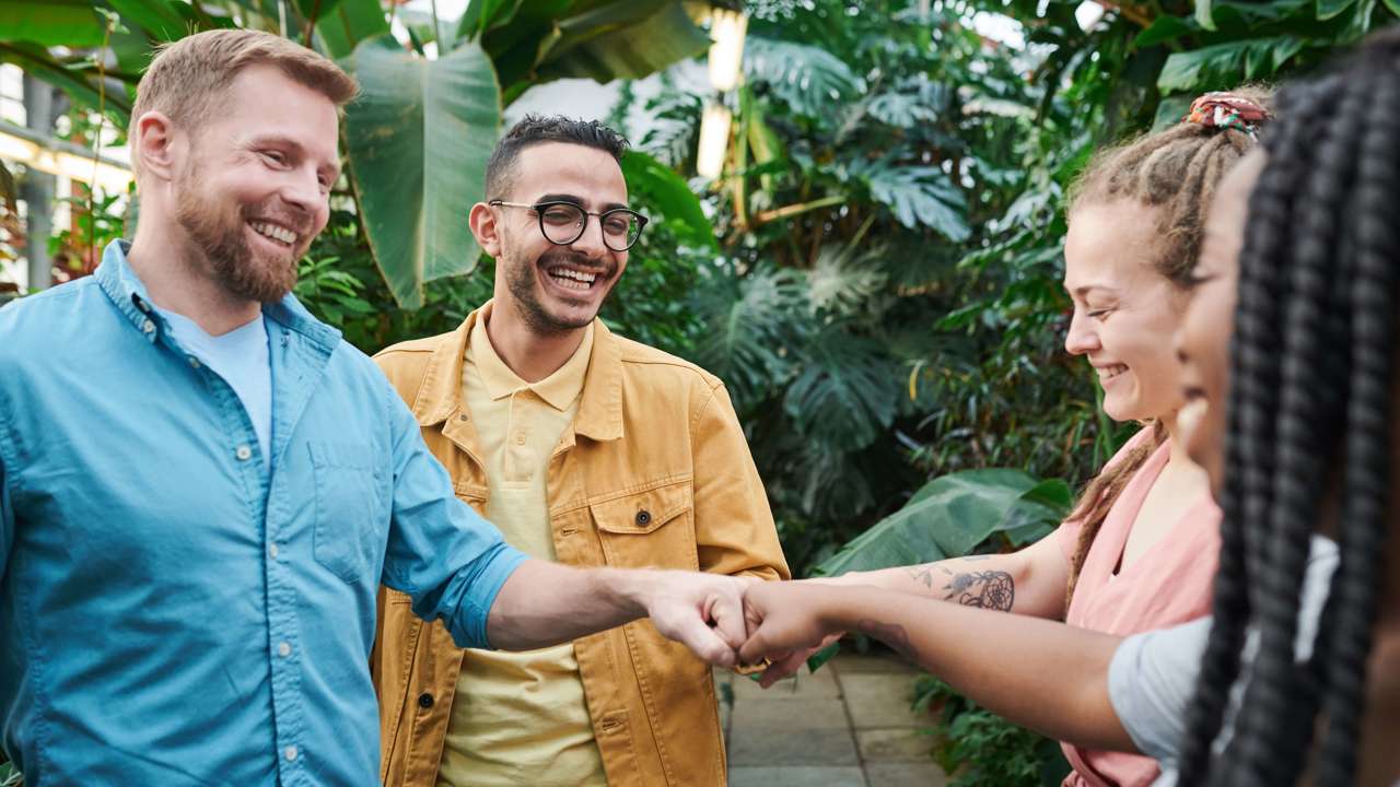 Four people fist bumping against tropical background