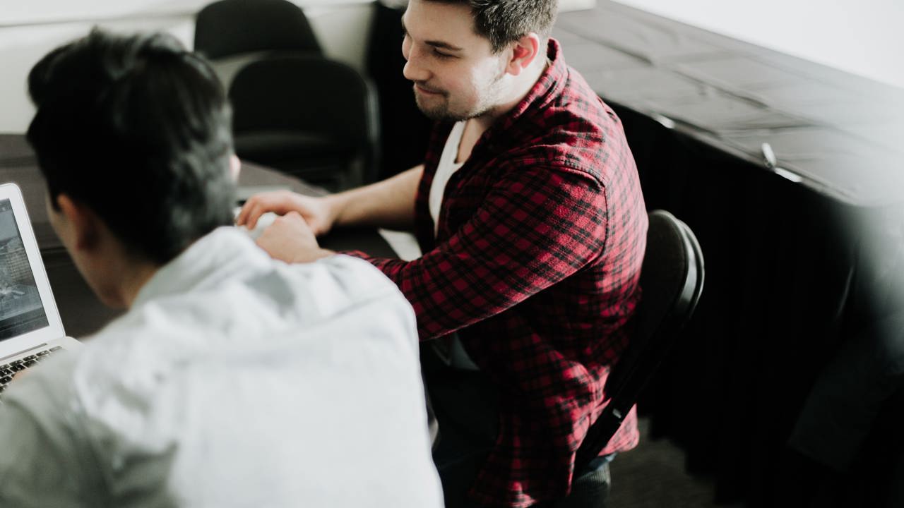 Two men sitting next to each other in an office