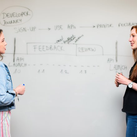 two woman writing on a whiteboard