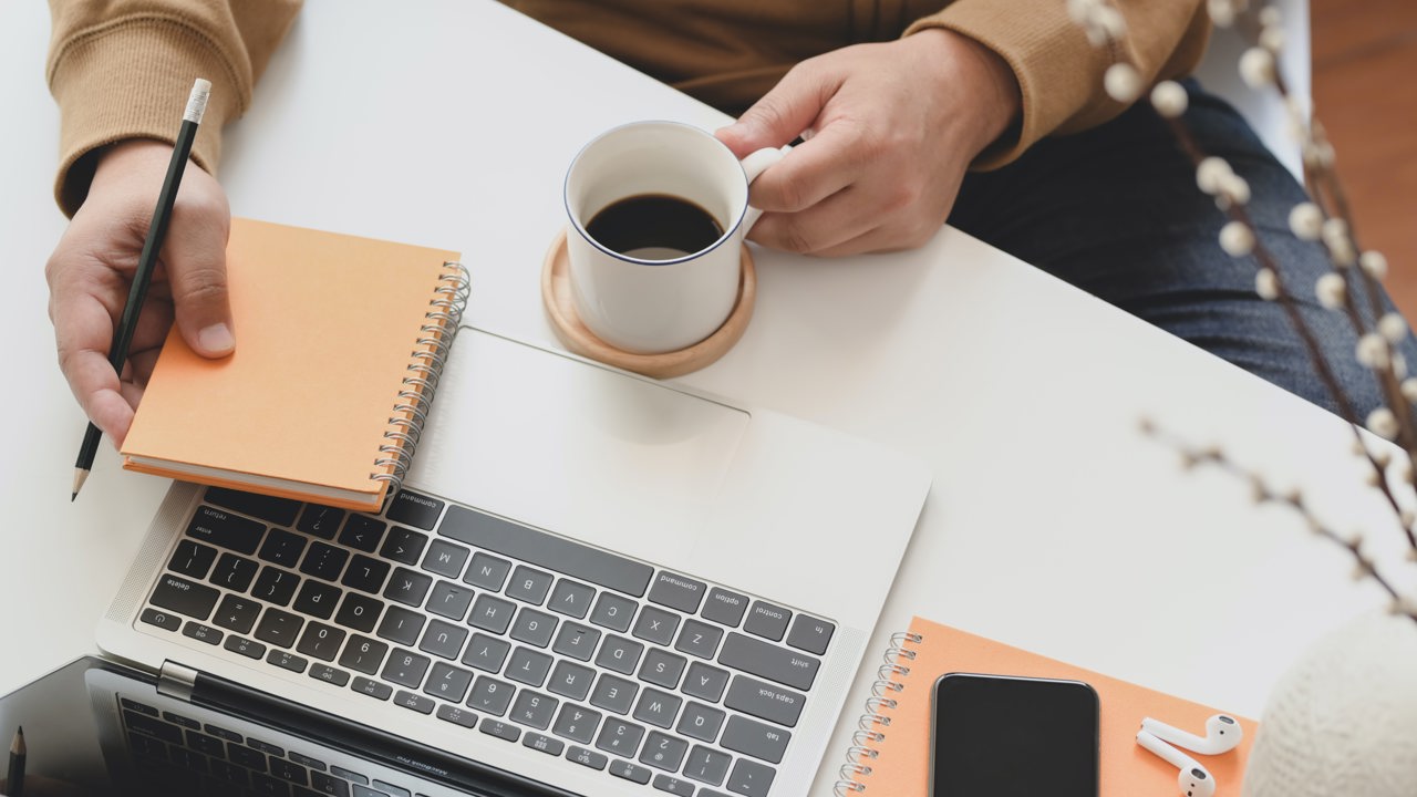 Person Holding White Ceramic Mug Beside Laptop