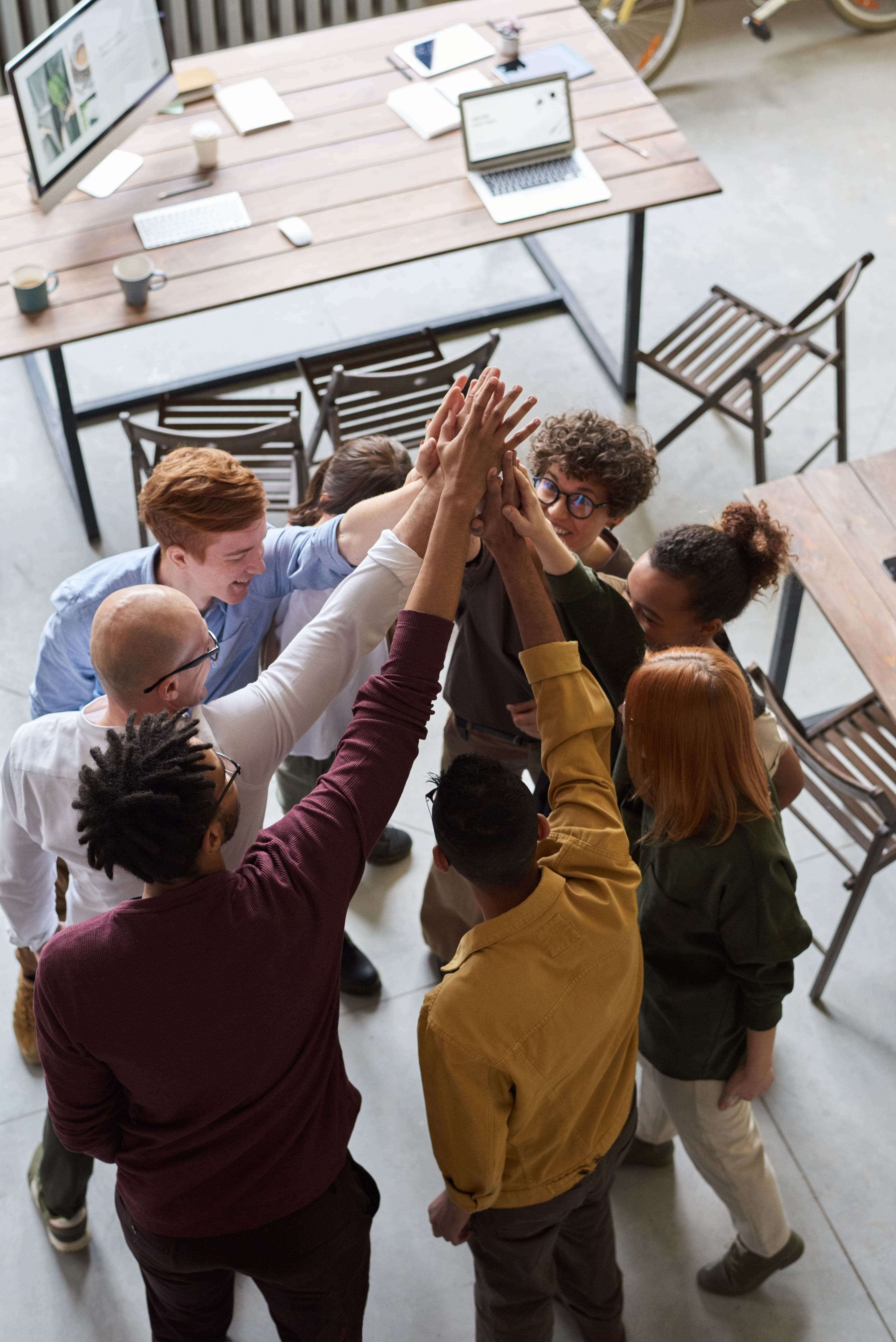 Top view of eight people doing a high five in a circle